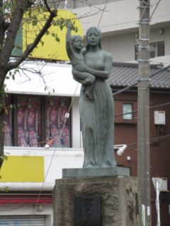桜の木の下の母子像@小田急電鉄江ノ島線の桜ケ丘駅西口ロータリー。